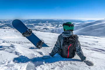 Snowboarder with snowboard relax on mountain top. Winter freeride snowboarding