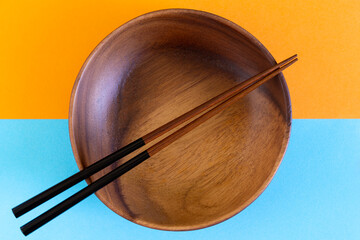 Asian wooden bowl, wooden plate, with chopsticks and without on Abstract pastel colored paper,...