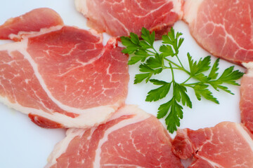 Raw Pork Slice in White Round Plate decorated with parsley. Fresh raw pork.