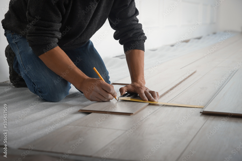 Wall mural Worker installing new laminate flooring in room, closeup