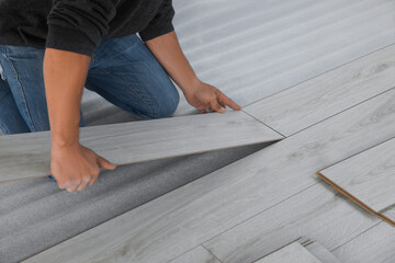 Worker installing new laminate flooring in room, closeup