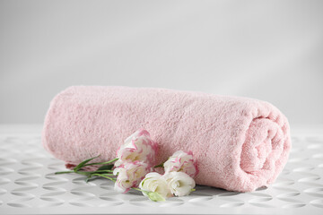 Rolled soft towel and eustoma flowers on white table