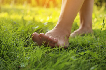 Woman walking barefoot on green grass, closeup