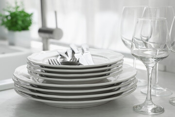 Different clean dishware, cutlery and glasses on countertop in kitchen, closeup