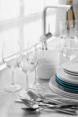 Different clean dishware, cutlery and glasses on countertop in kitchen