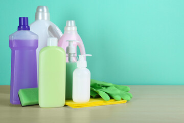Different cleaning supplies and tools on table against turquoise background, space for text