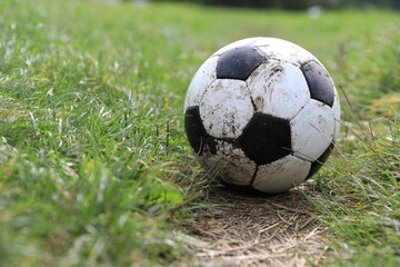 Dirty soccer ball on green grass outdoors, space for text