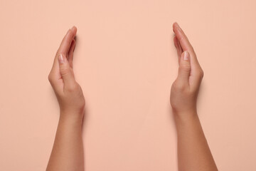 Woman holding on pale pink background, closeup of hands. Space for text