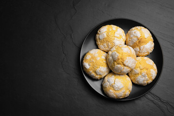 Plate with delicious lemon cookies on black table, top view. Space for text