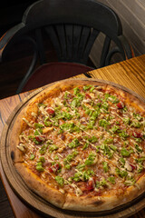 delicious pizza with cheese, greens, sauce in a restaurant
