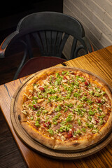 delicious pizza with cheese, greens, sauce in a restaurant
