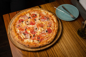 delicious pizza with cheese, greens, sauce in a restaurant
