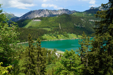 hiking trail overlooking scenic emerald-green alpine lake Haldensee surrounded by lush green woods in the Alps of the Tannheim valley or Tannheimer Tal, Tirol, Austria