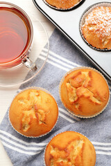 Flat lay composition with tasty muffins and tea on white wooden table