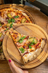 delicious pizza with cheese, greens, sauce in a restaurant
