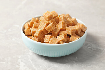 Brown sugar cubes in bowl on light grey marble table