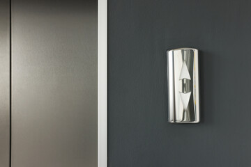 Elevator call buttons on grey wall, closeup