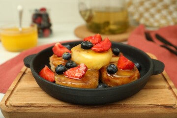 Delicious cottage cheese pancakes with fresh berries and honey served on table, closeup