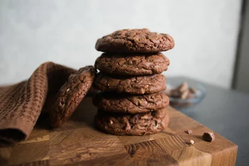 Tuinposter Selective focus shot of chocolate cookies on a wooden surface © Inna Prigodich/Wirestock Creators