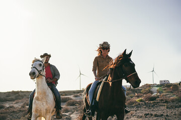 Young couple riding horses doing excursion at sunset - Soft focus on left horse face