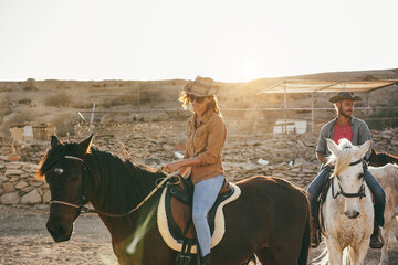 Young people riding horses doing excursion at sunset - Focus on woman hand