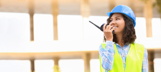 Portrait of female architect with two-way radio in building area