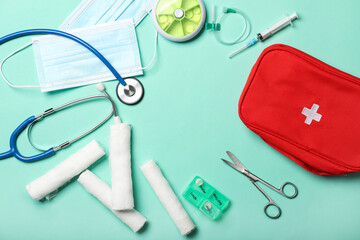 Stethoscope and first aid kit on color background