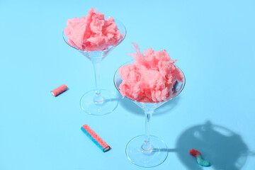 Glasses with delicious cotton candy on color background