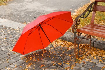 Stylish bright umbrella near bench in park