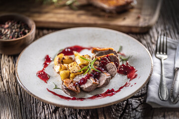 Culinarily prepared duck breast with baked potatoes and cranberry cauce