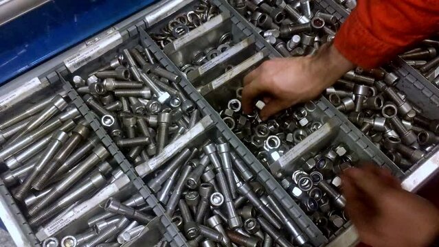 Worker locating the right nut and bolt drawer then taking the parts