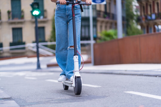 Detail of a young brunette woman moving in the city with an electric scooter, sustainable transport