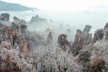 Aerial shot of the Wulingyuan foggy scenic area with sandstone pillars and peaks covered with grass