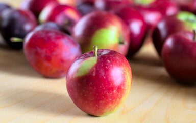 Concept for an simple autumn background. Close-up of fresh, organic fruit (apples, plums) on a wooden table. Shallow depth of field, copy space.