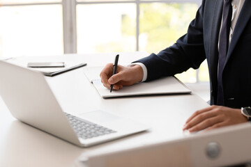 Young bank manager working with laptop at table in office
