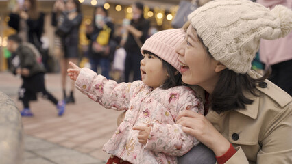 taiwanese mother and baby smiling with joy while having fun watching dancing fountain on a city...