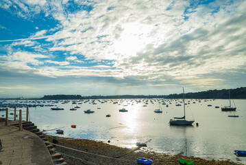 Obraz premium The marina of Dinard, Brittany, France, with many vessels moored. Sun and dramatic sky on the background.