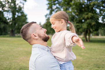 young father carrying daughter having fun enjoying time together outdoors in park.