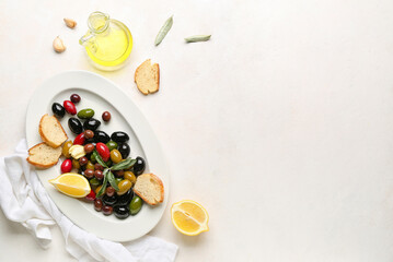 Composition with plate of different olives, bread and oil on light background