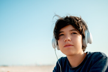 Teenager 13 years old listen to music on the beach by the sea