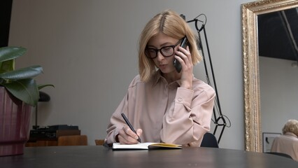 Adult woman in eyeglasses, laughing wearing pink shirt calling on the smartphone. Concept of conversation.