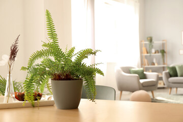 Vase with flowers and green houseplant on table in living room