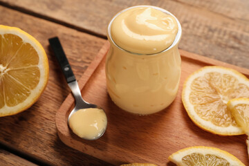 Board with jar of tasty vanilla pudding and lemon on wooden background, closeup