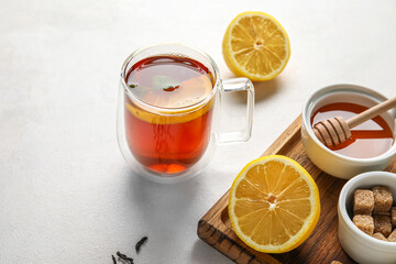 Glass cup of black tea with lemon, honey and cane sugar on white background, closeup