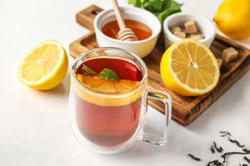 Glass cup of black tea with lemon and mint on white background, closeup