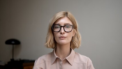 Portrait of blonde woman in eyeglasses smiling. Attractive stylish adult person looking at the...