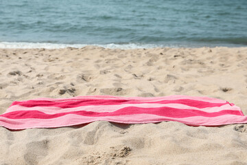 Pink striped towel on beach sand near sea