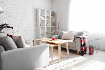 Interior of modern living room with grey sofas, table and tree branches