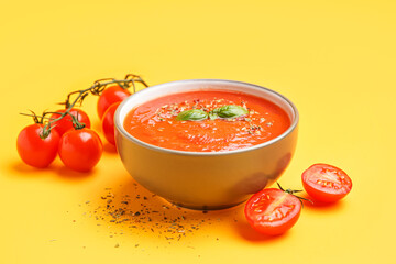 Bowl of tasty tomato soup on yellow background