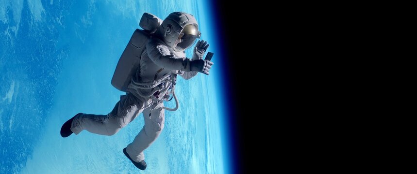Female astronaut having a video call on her phone while performing space walk in open space, Earth in the background